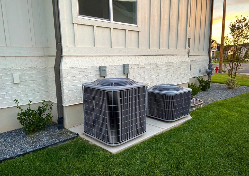 Two outdoor air conditioning units beside a house