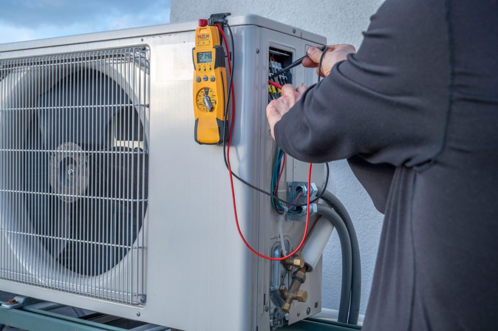 Technician working on an outdoor HVAC unit's electrical panel