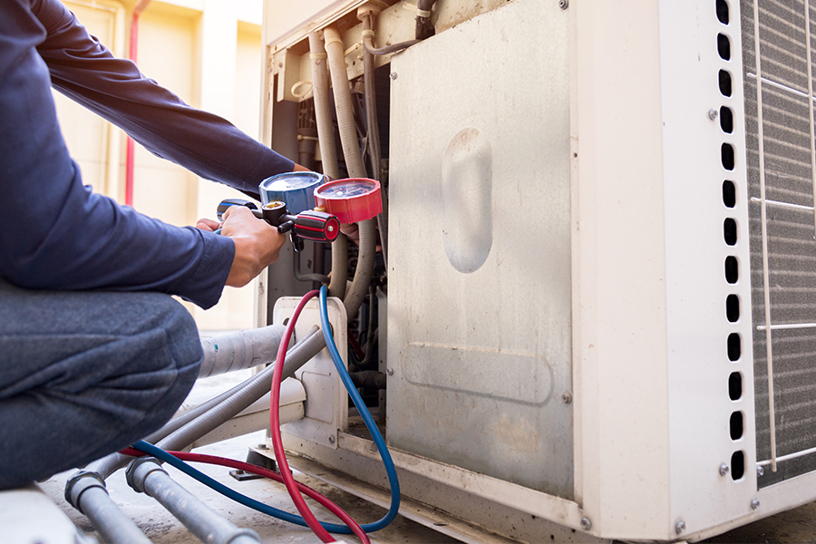 Technician using a pressure gauge to inspect an air conditioning unit