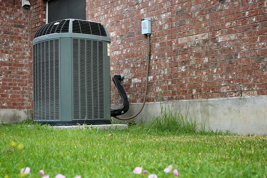 Outdoor air conditioning unit next to a brick wall