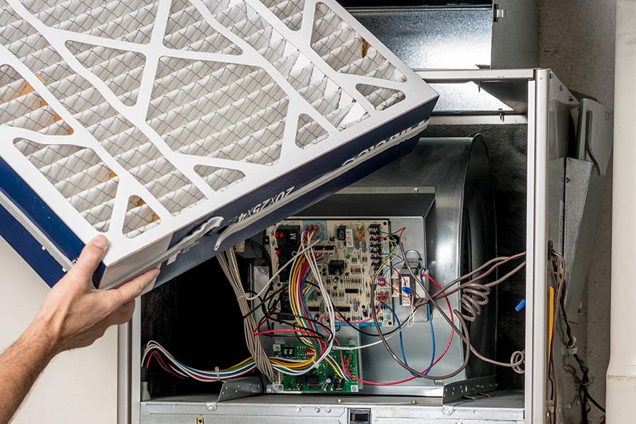 Person replacing an air filter in a furnace
