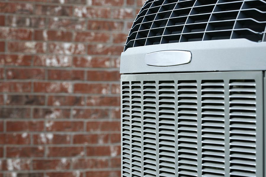 HVAC condenser unit next to a brick wal