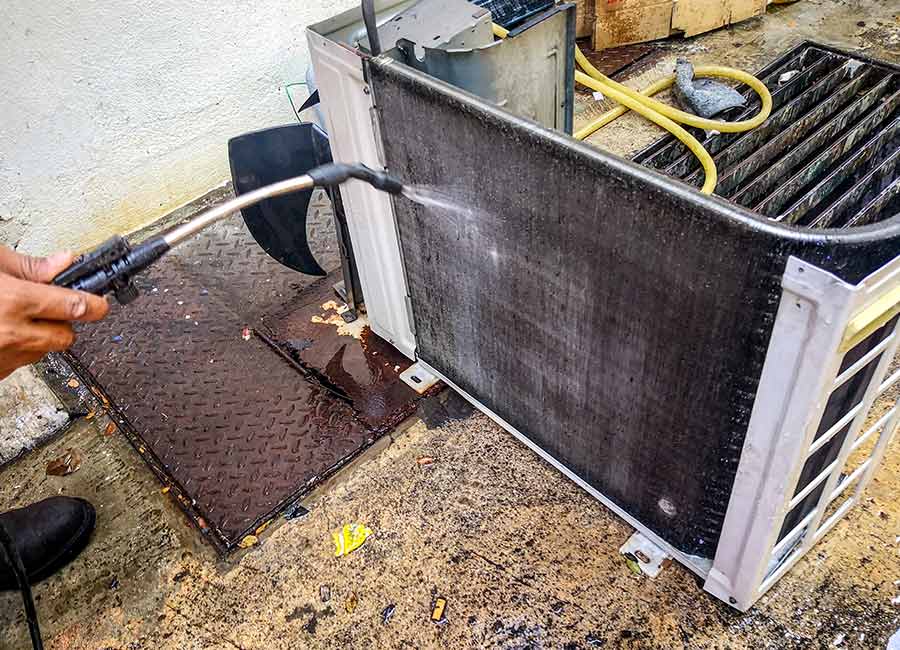 Person cleaning an air conditioner coil